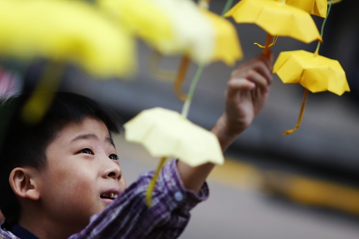 Un niño juega con paraguas de papel, el símbolo de los manifestantes prodemocracia
