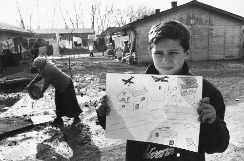 Un joven refugiado sostiene un dibujo con bombas lanzadas desde un avión
