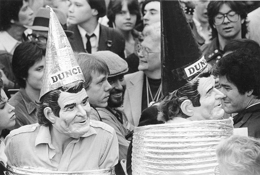 Hombres con máscaras de Ronald Reagan y gorras de burro en una manifestación política, Wisconsin, 10/12/1984.