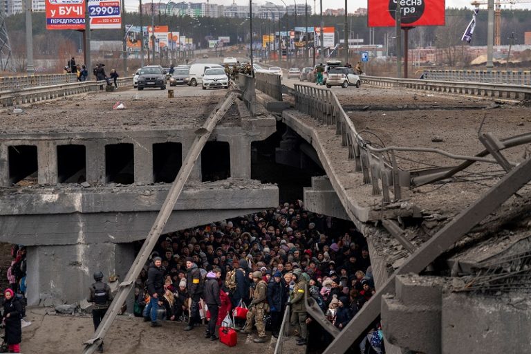 Ukrainians crowd under a destroyed bridge