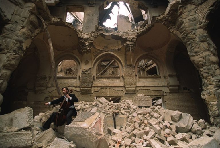 Vedran Smailović tocando en el edificio destruido de la Biblioteca Nacional de Sarajevo, en 1992. Imagen de Mikhail Evstafiev