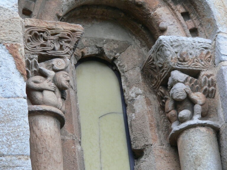 Dos capiteles con figuras exhibiendo unos desproporcionados órganos sexuales, iglesia de San Pedro de Cervatos, Cantabria