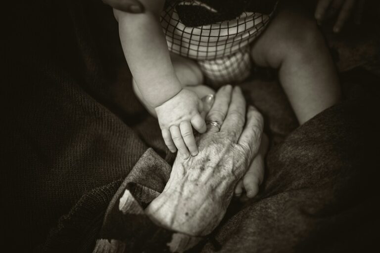 Una mujer mayor sosteniendo la mano de un bebé. Imagen de Rod Long